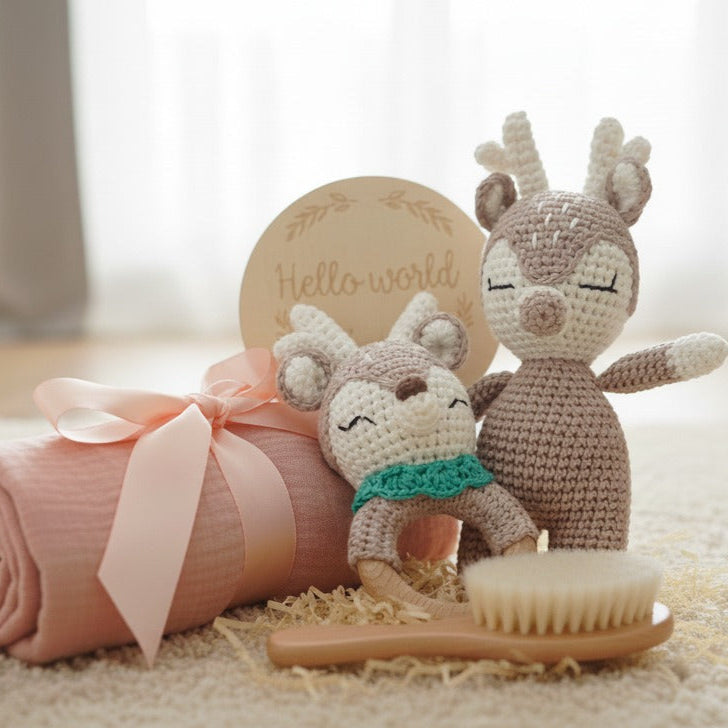 Baby items including a pink blanket, plush toys, and a 'hello world' sign on a light surface.